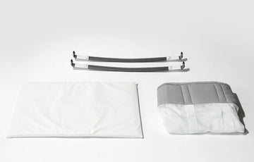Image at angle of a lay-down of The Bassinet Fabric Assembly, Bassinet Mattress, and  Bassinet Rocker Arms